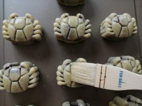 把月饼取出，用毛刷沾点蛋黄水（一个蛋黄+适量水，再过滤使用），在碗边轻扫一下，把多余的蛋黄水扫去，再刷月饼表面，侧面不用刷