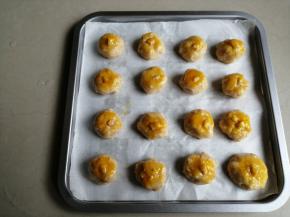分成16等份，搓圆，放在铺了油纸的烤盘上。为了让成品更好看，在表面粘上大粒的花生仁，再刷上一层蛋黄液，这样烤出来颜色金黄金黄的，非常好看