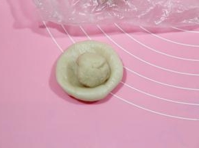 冷藏醒好的油皮，取出略回温一会，称一下油皮和油酥的重量，将油皮、油酥，每种分成12份。盖保鲜膜。防止油皮干掉。然后取一油皮，搓圆，然后放在左手掌心（我都是带PVC手套操作的），用右手掌心按扁，放上油酥。