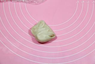 继续醒5分钟。取一个二擀好的卷，从中间按扁，将两头往中间按。