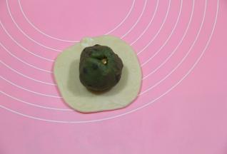 略按扁，用擀面杖轻柔擀开，顺一个方向擀，不耀来来回回的擀，会混酥，擀成圆形，放上馅料球。