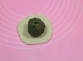 略按扁，用擀面杖轻柔擀开，顺一个方向擀，不耀来来回回的擀，会混酥，擀成圆形，放上馅料球。