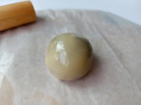 放上豆沙馅、面团放于左手虎口位置，用大拇指的大鱼际部位推面皮、推的过程中转动面团，让面皮慢慢的包裹在馅上并收口。