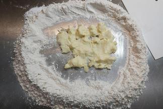 把软化好的黄油跟糖粉到在面粉中间，带上pvc手套抓匀。