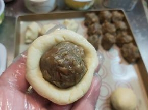 把面皮搓圆、压扁，包住馅料收拢滚圆。