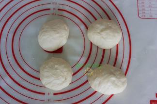 揉搓排气，然后分成四等分，再次滚圆面团。盖上保鲜膜，进行15分钟的中间发酵。