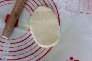 把中间发酵好的面团，用擀面杖擀成椭圆形，面团非常松软，要防粘。从上往下卷来，卷面团的时候要往里面收紧，这样做出来面包形状漂亮。