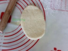 把中间发酵好的面团，用擀面杖擀成椭圆形，面团非常松软，要防粘。从上往下卷来，卷面团的时候要往里面收紧，这样做出来面包形状漂亮。