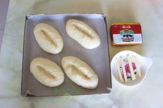 发酵好的面包胚，用剪刀，在面包上划出一个口，黄油切4个小长条，软化之后，放入面包剪好的口上。如果完全软化黄油，建议用挤压的方式，在面包切口上。