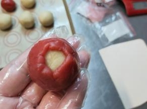 一点一点慢慢收紧，在顶部留一个小口。（在这个过程中一定注意要馅料跟皮完全贴紧，否则进入空气，做好的月饼会走型）