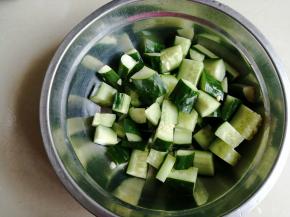 黄瓜切丁，加入盐，抓匀几下，先腌20分钟，这样会有一些水分渗出，再用手抓干黄瓜水分