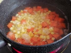 锅里的水烧开后，倒入玉米粒和胡萝卜丁，水开后煮5分钟，再捞起来，沥干水分