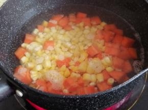 锅里的水烧开后，倒入玉米粒和胡萝卜丁，水开后煮5分钟，再捞起来，沥干水分