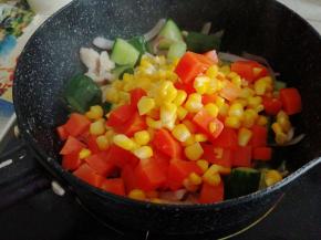 倒入玉米和胡萝卜丁，加入适量盐，翻炒