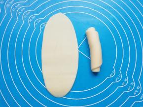 包好的油酥皮擀开，然后卷起来，收口朝下摆放，盖上保鲜膜备用。