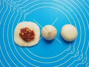 放上肉馅，用虎口慢慢向上推挤收口，将收口捏紧，反过来收口朝下摆放，用手掌轻轻压平成饼状。