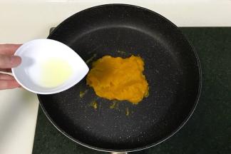 南瓜泥入不粘锅中，分三四次加入糖粉和玉米油翻炒，南瓜泥会越来越稠。