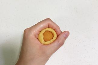 取一个面团按扁，放上一份南瓜馅，利用虎口收紧，搓成椭圆形，依次完成。