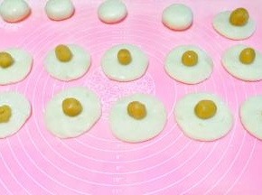 揉成饼状，放入搓成圆球的馅料，包好收口。放手粉中滚一圈。