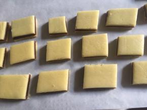 首先180度预热烤箱，然后将面片切成若干个小方块，小心移入垫上油纸的烤盘中，为了避免面片烘烤膨胀黏连在一起，因此注意面片中保持一定的间隔空隙；

