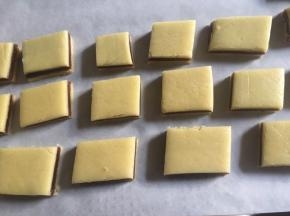 首先180度预热烤箱，然后将面片切成若干个小方块，小心移入垫上油纸的烤盘中，为了避免面片烘烤膨胀黏连在一起，因此注意面片中保持一定的间隔空隙；

