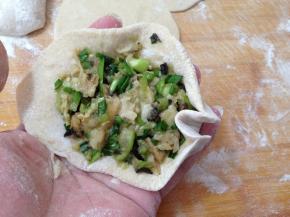 用中指把面皮按向馅料方向，用手捏挤，然后用大姆指和食指托起两旁的面皮，只其形成W形