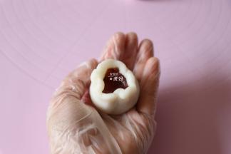 像包汤圆那样一手按住内馅一手借助虎口边旋转边收紧收口；