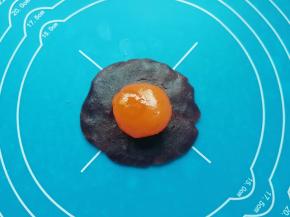 油酥皮松弛的时间里把蛋黄酥的馅做好：红豆沙馅分成28份（差不多17-18g一份）搓圆，用手压扁放上一个咸蛋黄，包住咸蛋黄搓圆。