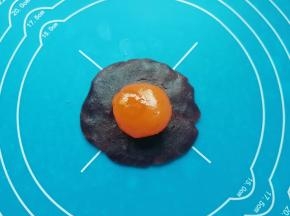 油酥皮松弛的时间里把蛋黄酥的馅做好：红豆沙馅分成28份（差不多17-18g一份）搓圆，用手压扁放上一个咸蛋黄，包住咸蛋黄搓圆。