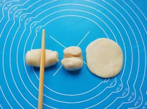 松弛好的卷卷用筷子从中间压一下，两头向上压扁，擀成圆形的饼皮。