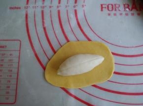 黄色面团擀成薄的椭圆形，长度比白色面团长一点。在表面抹一层玉米油（配方外），接口处不抹油，放上白色面团