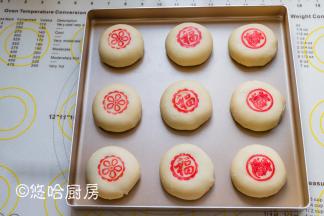 包好的月饼摆放在烤盘中，用手压扁。红色素用适量的清水溶解开，用模具沾色素盖在月饼上。