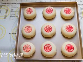 包好的月饼摆放在烤盘中，用手压扁。红色素用适量的清水溶解开，用模具沾色素盖在月饼上。