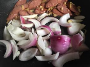 推至一旁放入洋葱；（因为洋葱相对难熟，所以喜欢洋葱吃熟一点可以先将牛肉肠片装盘，将洋葱炒至6分熟以上）
