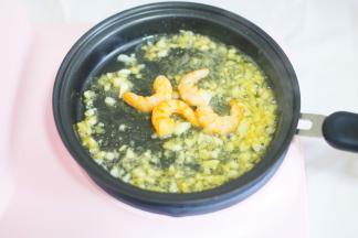 多功能早餐机炒锅烧热加油，加入剩余的大蒜爆香，加入虾仁炒香。