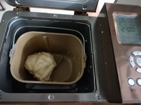 启动和面程序13分钟（不同型号的面包机和面时间不同），和面结束，在面包桶上盖上湿布，再盖上面包机盖，面团发酵两倍大。室温高的话不用开启面包机的发酵功能