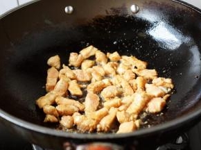 起锅热油，油热下入鸡丁翻炒，变色后捞出。