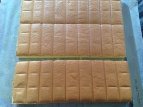 烘烤好的蛋糕取出，晾3分钟后倒扣在烤架上，撕掉油纸，将四周的边切掉，再切成三等份