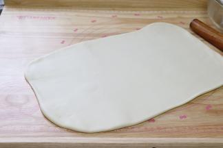 用擀面杖，把面团擀成长方形的大面片。