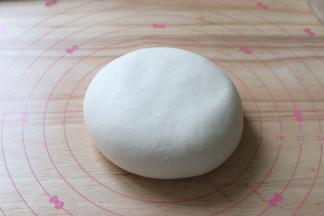 静置好的面团，压扁。面团经过静置以后，更加的细腻延展性也更好。