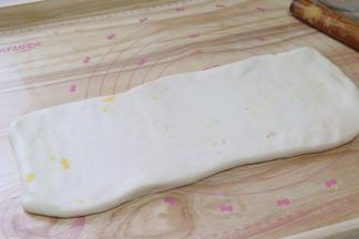 继续折，形成了一个长条的面片，把收口捏一捏，用擀面杖稍微擀薄。