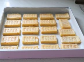 一块一块放到垫了油纸的学厨方形烤盘中，用叉子扎出小孔。