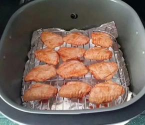 将腌好的鸡翅正面朝上、放置空气炸锅的高架网上