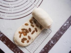 将面团再次擀开，放入提前浸泡清洗并沥干水分的葡萄干，从一侧卷起