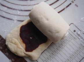 将面团再次擀开，放入豆沙馅儿抹平，从一侧卷起