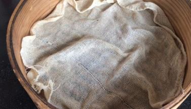 屉布浸湿后拧干水分，铺在蒸屉上