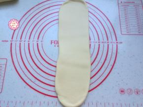 把卷好的面团竖向按扁，再次擀开成长条形状，擀的时候注意要从中间向两头擀，宽窄一致。