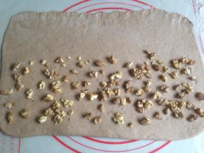 面团多揉揉，排气，擀成长方形，其中一条长边擀薄一些，在2/3处撒上核桃仁