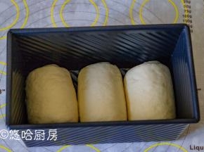 松弛后的面团再次擀开，翻面后卷起，底部朝下摆放在模具中。盖保鲜膜放入烤箱中进行二次发酵，此时不开烤箱哈，烤箱里面可以放一碗热水，增加温度和湿度。