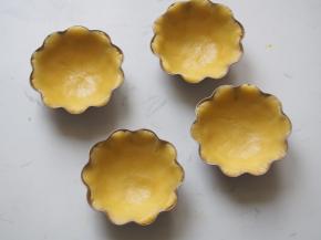 将冷藏好的挞皮分成12份，放在菊花蛋挞模中，轻轻推匀